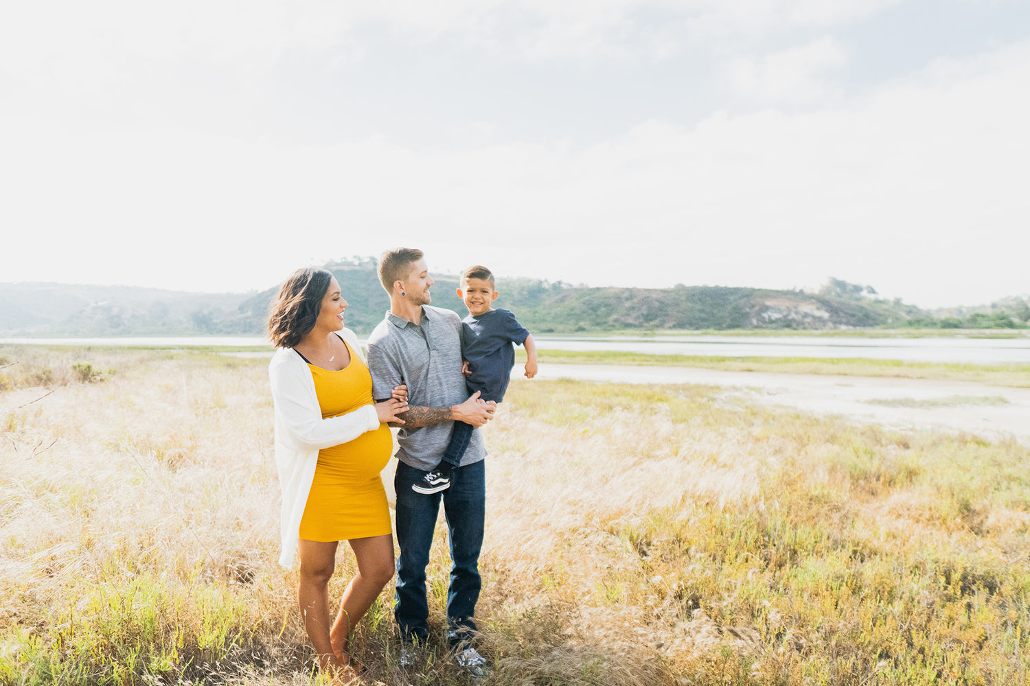 Founders of LuvBelly prenatal powder pose for family photo in field.